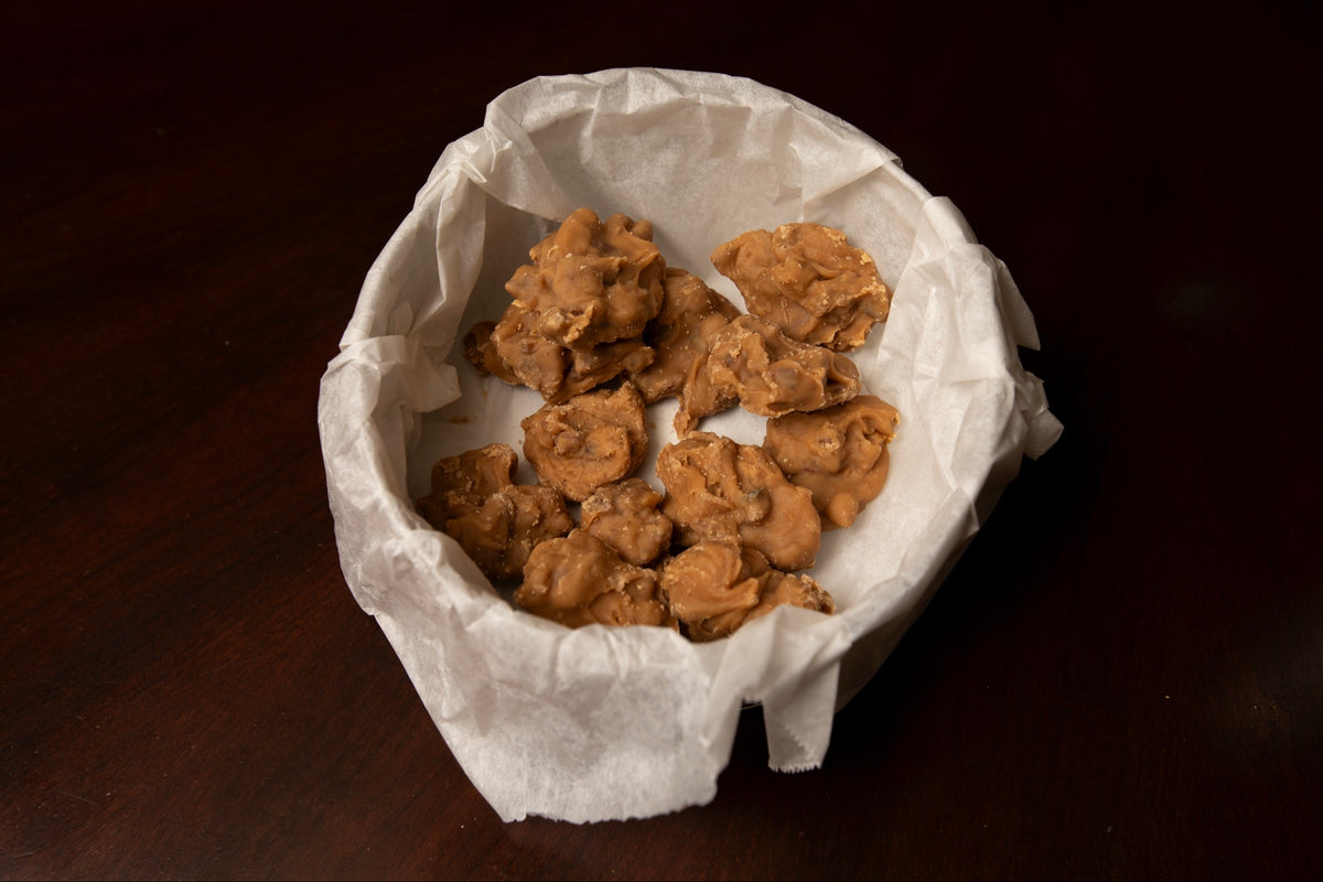 Twenty bite-size Creole-ish pecan candy pralines in a parchment-lined tin