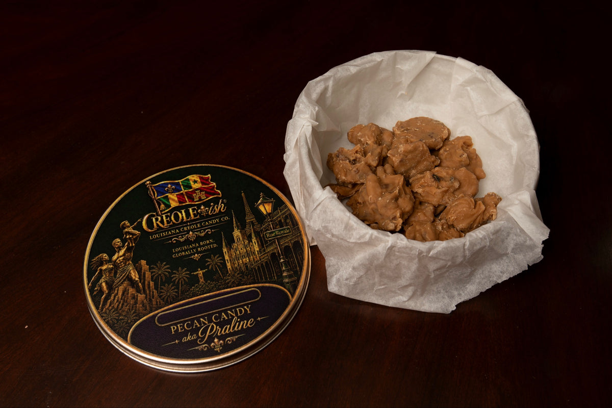 Creole-ish gold tin lid beside 20 Creole-ish Bites pecan praline bites packed in parchment paper